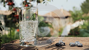 Water is poured into glass. Drinking water is poured into transparent glass glass on background of country house and