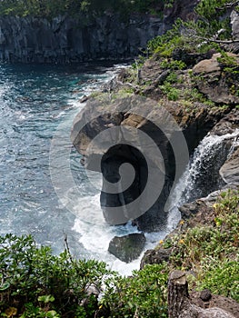 Water pouring down into the sea over the cliffs of the volcanic rocky coast