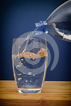 Water pouring into glass against blue background