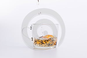 Water pouring into glass cup with black tea and lemon Isolated on white