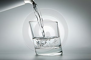 Water pouring into a glass on a gray background
