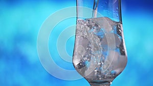 Water pouring into glass with ice slow motion fresh natural cool with bubbles.