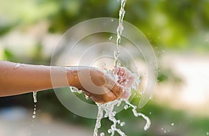 Water pouring in kid hand on nature background, environment issues