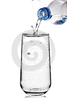 Water pouring from a plastic bottle into a glass isolated on white background