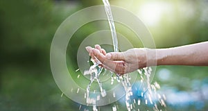 Water pouring in woman hand on nature background