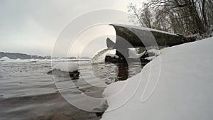 Water pours from the the waste-pipe into the river in winter