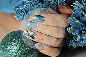 Water procedures. A newborn little boy swims in the water .Christmas winter nail design with different colors and patterns of nail