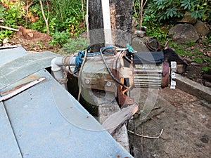 a water pump that looks worn out due to its long use and is still installed in a dug well