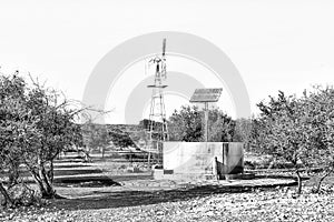 Water-pumping windmill and solar panels for a waterpump. Monochrome photo