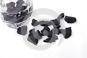 Water purified by shungite stones in a glass on a white background