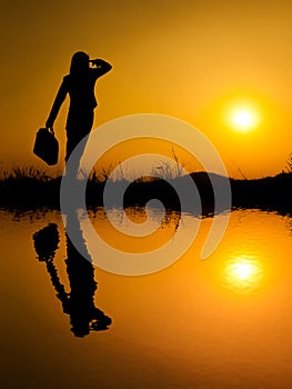 Water Reflect of Business woman standing and holding bag at suns