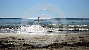 Water reflection of a silhouette of a man standing on a paddle board and doing water sports at sea.