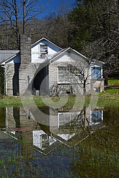 Water reflections of a little gray house after a rain.