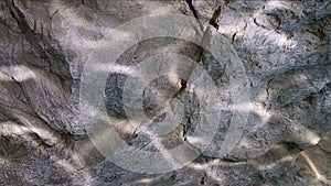 Water ripple caustic light reflections on stone wall