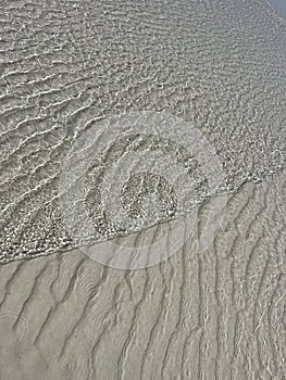 Water ripples over beach sand patterns