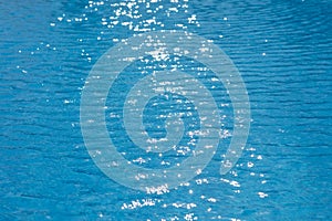 Water ripples texture in swimming pool with sunny glare