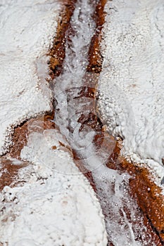 Water running between salt crystal deposits in evaporation ponds at Maras, Peru