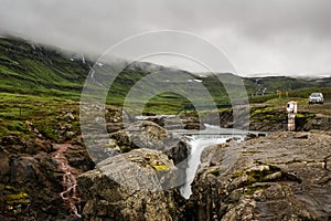 Water running in the Seydisfjordur fjord on the east coast of Iceland surrounded by mountains on a cloudy day