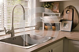 Water running from the tap into a kitchen sink. Clean and drinking water. Save water and enviromental concept