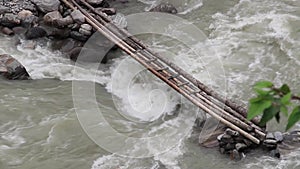 Water rushing in a Himalayan river under a small wooden bridge, Nepal