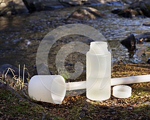 Water sampler, container and cover on river bank.