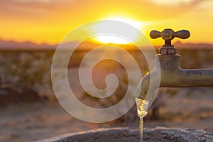 Water scarcity concept with faucet in desert at sunset. Environmental issues