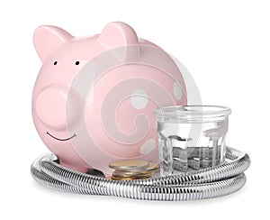 Water scarcity concept. Piggy bank, shower hose, coins and glass of drink on white background