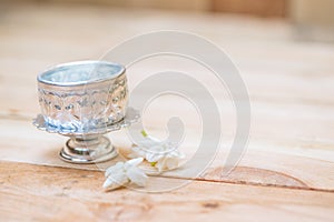 Water in silver bowl with jasmine white flower.