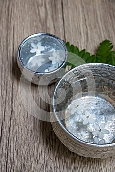 Water in silver bowl with white flower.