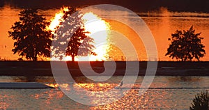 Water skier pulled by ski lift during sunset time