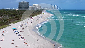 Water, sky, and city buildings form a picturesque background to a crowded beach, capturing the leisurely travel