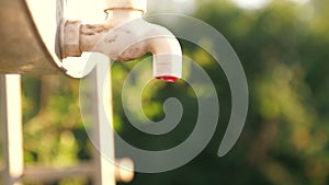 Water is slowly dripping from the tap. Drops of water flow down from an outdoor tap.