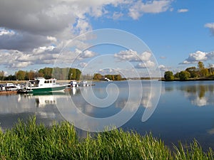 Water smooth surface of the river Kotorosl with reflecting clouds, pier with motorboats, Yaroslavl