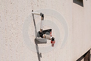 A water spigot with a green hose springs a leak