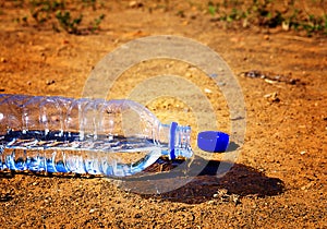 Water spilling from plastic bottle  on a droughty place