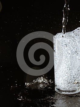Water splash and crystal glass on black background