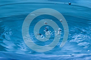 Water splash in dark blue color with a drop of water flying from