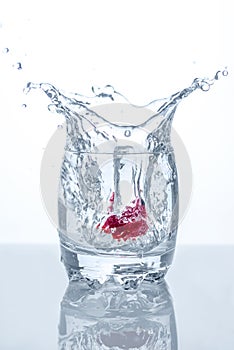 Water splash in a glass with red strawberry in it.