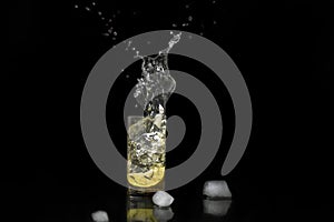 Water splash, lemon in the glass with water and ice cubes Isolated on Black Background