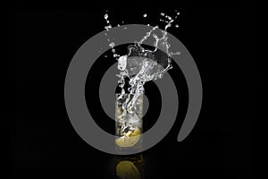 Water splash, lemon in the glass with water and ice cubes Isolated on Black Background