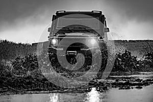 Water splash in off-road racing. Beautiful nature. Classic 4x4 car crossing water with splashes on muddy road. Offroad