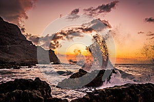 Water splash. Sea waves breaking on rocks in the sunset. Waves splashing on rocks in the ocean. Playa de las arenas beach on