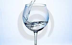 Water with splashes poured into the glass on a white background.