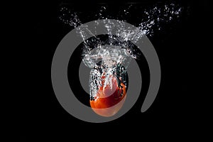 Water splashes from a tomato that has fallen into the water