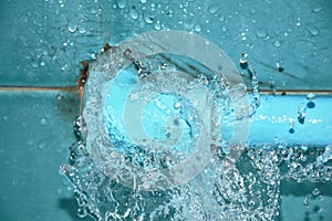Water splashing from broken plumbing blue polythene pipe line in bathroom