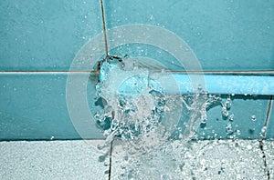 Water splashing from broken plumbing blue polythene pipe line in bathroom