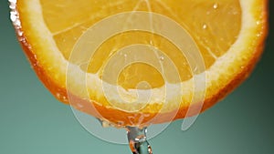 Water splashing on fresh orange in slow motion. Water dropping from citrus fruit. Close up orange slice rich in vitamin