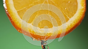Water splashing on fresh orange in slow motion. Water dropping from citrus fruit. Close up orange slice rich in vitamin
