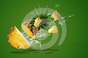 Water Splashing on Fresh Pineapple is tropical fruit isolated on Green background