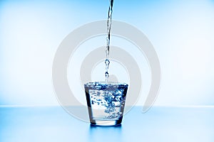 Water splashing from glass isolated on blue background